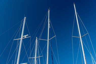 several masts of a yacht without sails against a blue sky
