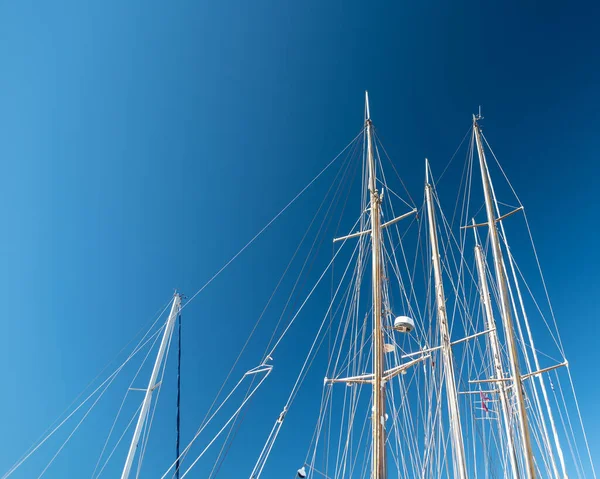 several masts of a yacht without sails against a blue sky