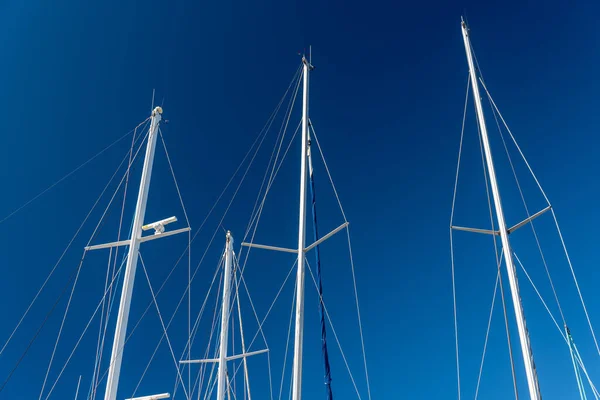 several masts of a yacht without sails against a blue sky