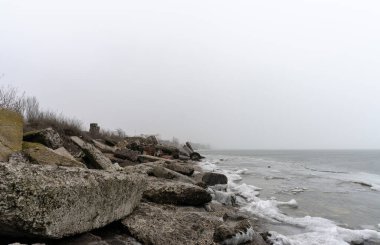 sea with ice and dirty snow and a beach without people in Ukraine in winter