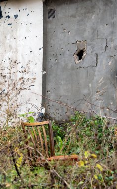 old vintage chair on the background of a wall with a hole from a mine war in Ukraine with Russia