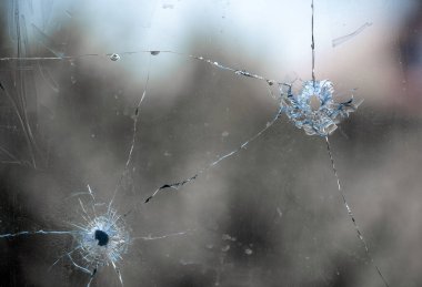 bullet hole in window glass with cracks abstract background close war