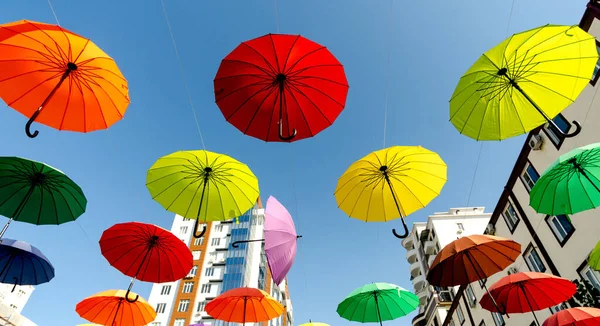 许多色彩斑斓的雨伞在城市街道的抽象背景上飘扬 — 图库照片