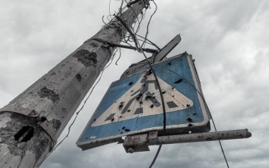 concrete pillar broken by shards and blue road sign against a gloomy sky in Mariupol Ukraine