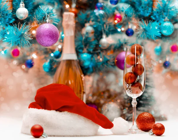 red glitter balls in a large wine glass against the background of a decorated blue Christmas tree
