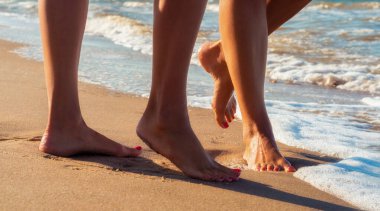 yaz aylarında deniz sörf dalgalarında kumlu bir plajda kadın ayakları yakın