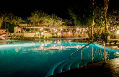 Sharm El Sheikh, Mısır - 02 06 2018: gece, otelin göl havuzunda palmiye ağaçlarındaki boş koltuklar suya yansıyan fenerler.