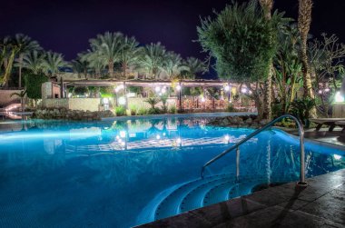 Mavi su havuzu ve geceleri sokak lambalı yeşil palmiye ağaçları. Sharm el Sheikh Mısırlı insanlar olmadan.