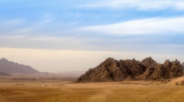 Çöl manzarası ve yüksek kayalık dağlar mavi gökyüzüne karşı ve Mısır 'da Sharm El Sheikh' de bulutlar.