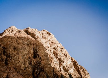 açık mavi gökyüzüne karşı yüksek kayalık dağ