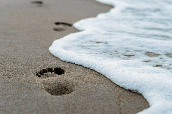 footprints in the sand on the beach near the surf