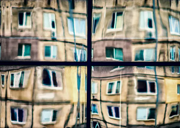 crooked reflection of houses in the glass of the window abstract colored background