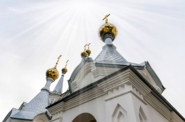 Hıristiyan kilisesinin haçlarıyla altın kubbeler ve gökyüzünden gelen ilahi ışık huzmeleri.