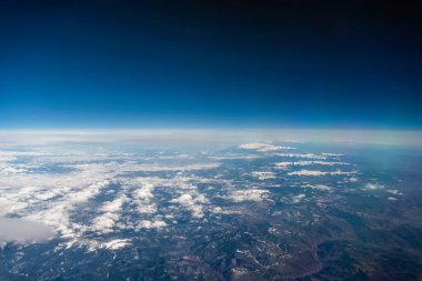 Panorama manzarası uçak penceresinden dağlara bulutlar ve mavi gökyüzüne