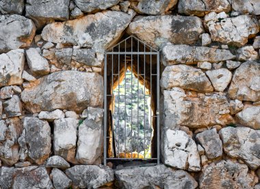 old stone antique wall with closed grate door