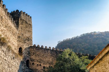 Gürcistan 'da ormanlı dağların arkasındaki eski kalenin kulesi ve duvarları.