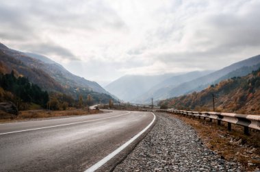 Gürcistan 'da sonbaharda öğleden sonra bulutlu arazi dağ yolu ve gökyüzü