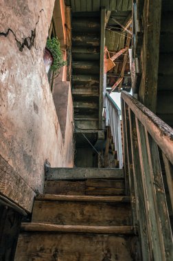 Tiflis 'te Gürcistan' da duvarında çatlak ve camında yeşil bir çiçek olan eski bir vintage evin merdiveninin ahşap basamakları.