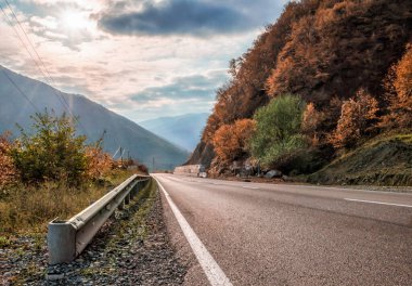 Gürcistan 'da sonbaharda güneş ışığı ve bulutlu manzara dağ yolu ve gökyüzü