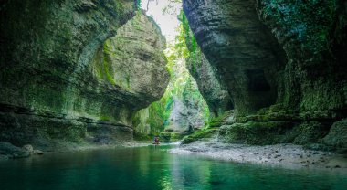 Gürcistan 'da bir kanyonda yüksek uçurumları, yeşil bitkileri ve turistleri olan dağ nehri.