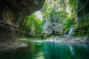Gürcistan 'ın Martville Kanyonu' nda sonbaharda yeşil bitkilerle dolu yüksek kayalıklar arasında nehir ve dere