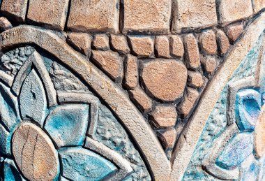 Parlak güneş ışığı altında tuğla ve çiçeklerden yapılmış renkli taş dokusu