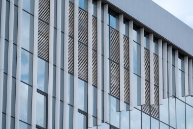 Gökyüzünün cam mimari arka planda yansıması olan modern bir binanın boş cam pencereleri.
