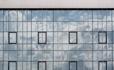 Gökyüzünün cam mimari arka planda yansıması olan modern bir binanın boş cam pencereleri.