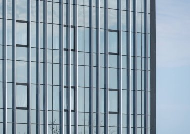 Gökyüzünün cam mimari arka planda yansıması olan modern bir binanın boş cam pencereleri.