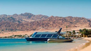 Mısır 'da palmiye ağaçları ve yüksek kayalık dağlar ile plajın arka planda sörf iki tekne