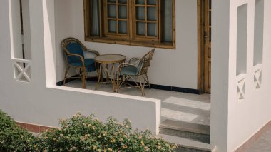 sandalye ve bir yuvarlak masa ve yakın yeşil bir çalı ile resort binasının Teras