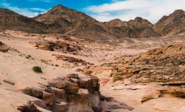 dağlar ve mavi gökyüzü beyaz bulutlar ile bir arka plan üzerinde çöl Kanyon