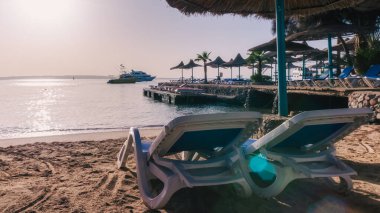 Kızıl denizin arka planında plaj şemsiyeleri ve palmiye ağaçları ve Mısır hurghada 'da gemiler.