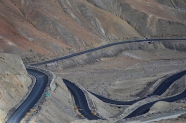 Sarmal yollar Hindistan 'ın Ladakh kentindeki engebeli ve çorak bir arazide kıvrılır. Dik tepeler ve kayalık arazi arasında zikzak çizer. Asfalt, etrafındaki dağların kurak toprak tonlarıyla keskin bir tezat oluşturuyor..
