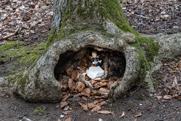 Little angel with a guitar inside a hole of a tree in the middle of the forest