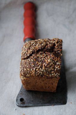 Çoklu tahıllı siyah ekmek ve eski bir bıçak ya da helikopter. Kenevir masa örtüsü arka planı. Retro biçimi.