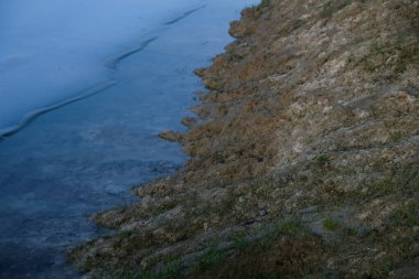 Yapay bir göletin donmuş yeraltı suları. Çamur nemli toprak.