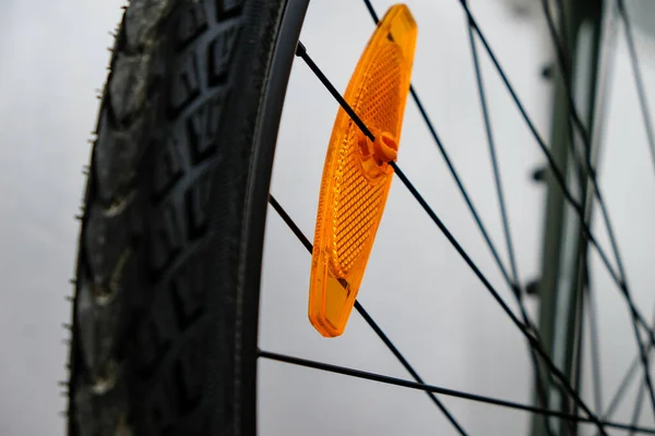 Bike reflector. A simple orange plastic cataphote on a bicycle wheel. Safe driving in the dark.