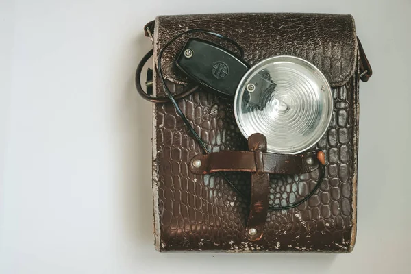 Old photo flash lamp in the leather bag. Vintage photo flash bulb. Copy space.