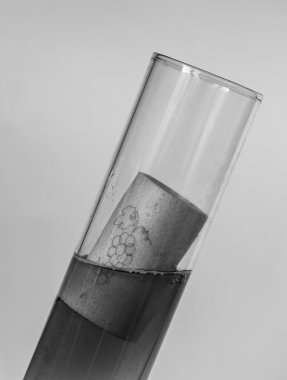 Artificial wine cork is in the beaker of wine. Black and white. 