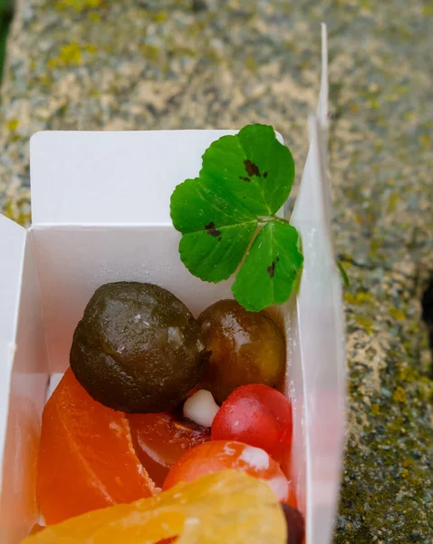 Confit fruits in the package box. Green clover leaf.