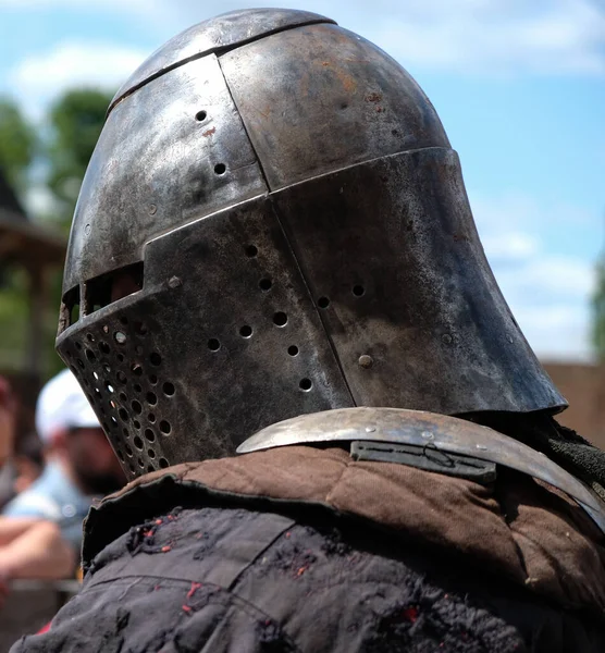 Profile of a knight in a metal medieval helmet.