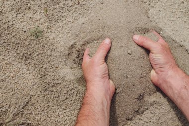 Avuçlar temiz kum dolu. Güçlü erkek elleri. Boşluğu kopyala.