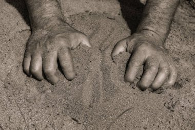 Erkeklerin elleri kumu kazıyor. Eylemlerde gerginlik.