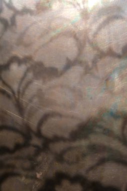 Bakır bir arka planda çiçek deseninin yansıması. Güneş ışığı. Seçici odak.