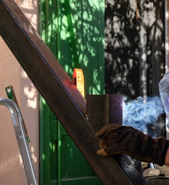 Kaynak evde işe yarıyor. İş eldiveni giymiş bir el. Kaynak merdiveni.