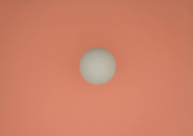 White egg on peach color background. Minimalism. Top view. Copy space.