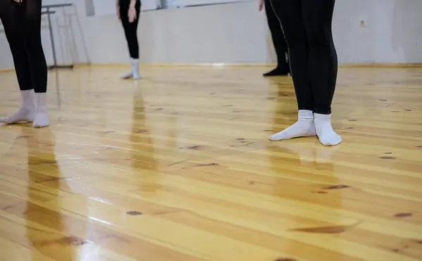 Contemporary dance workout. Woman\'s feet in white socks on the parquet floor. Shallow depth of field. Copy space.