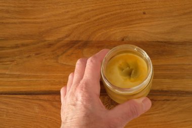 Woman's hand. Wax Protective Coating for wooden furniture in the glass jar. Table surface. Top view. clipart