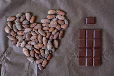 Kakao çekirdeği. Kalp. Çikolata. Fasulyeden bara çikolata üretimi. Kahverengi arkaplan.